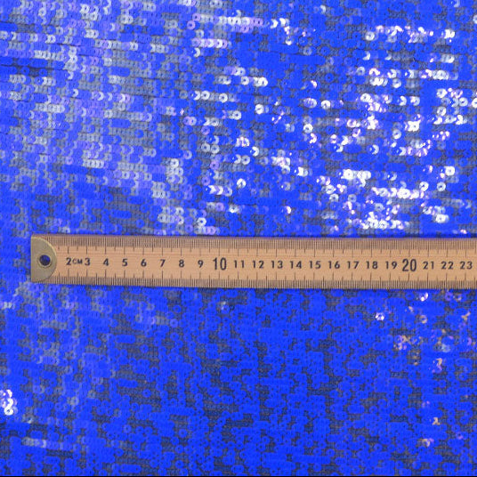 Blue fabric with white sequins and a ruler at the bottom for scale.